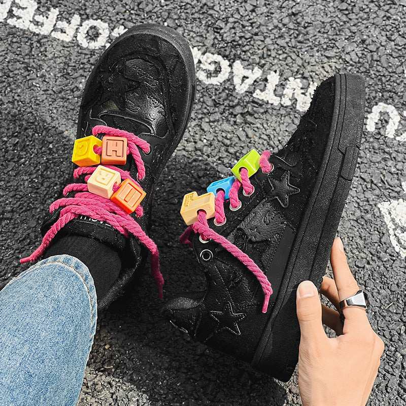Black sneakers with colorful shoelaces on a textured surface