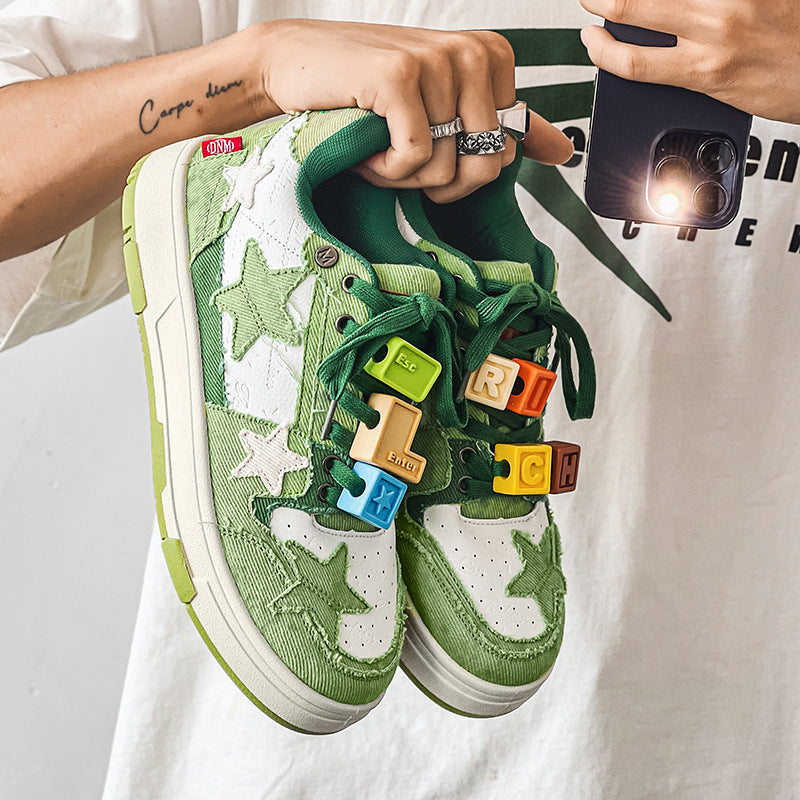 Green sneakers with colorful puzzle piece designs held by a person.